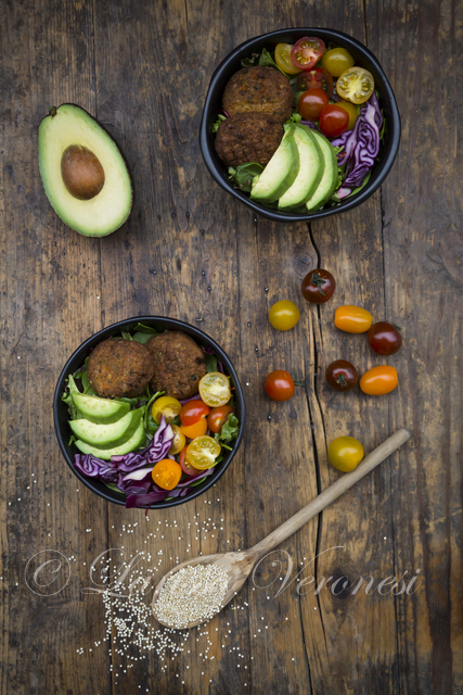 Lunch bowl mit Avocado, Quinoa-Bratlingen, Tomaten und Rotkohl